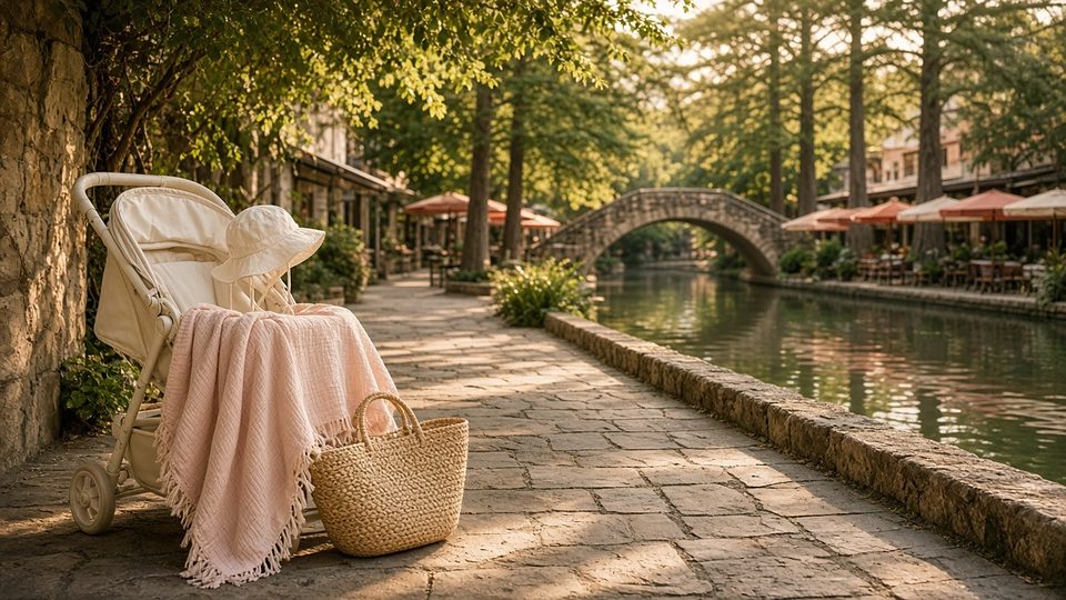 A stroller on the shady San Antonio River Walk beside a stone footbridge